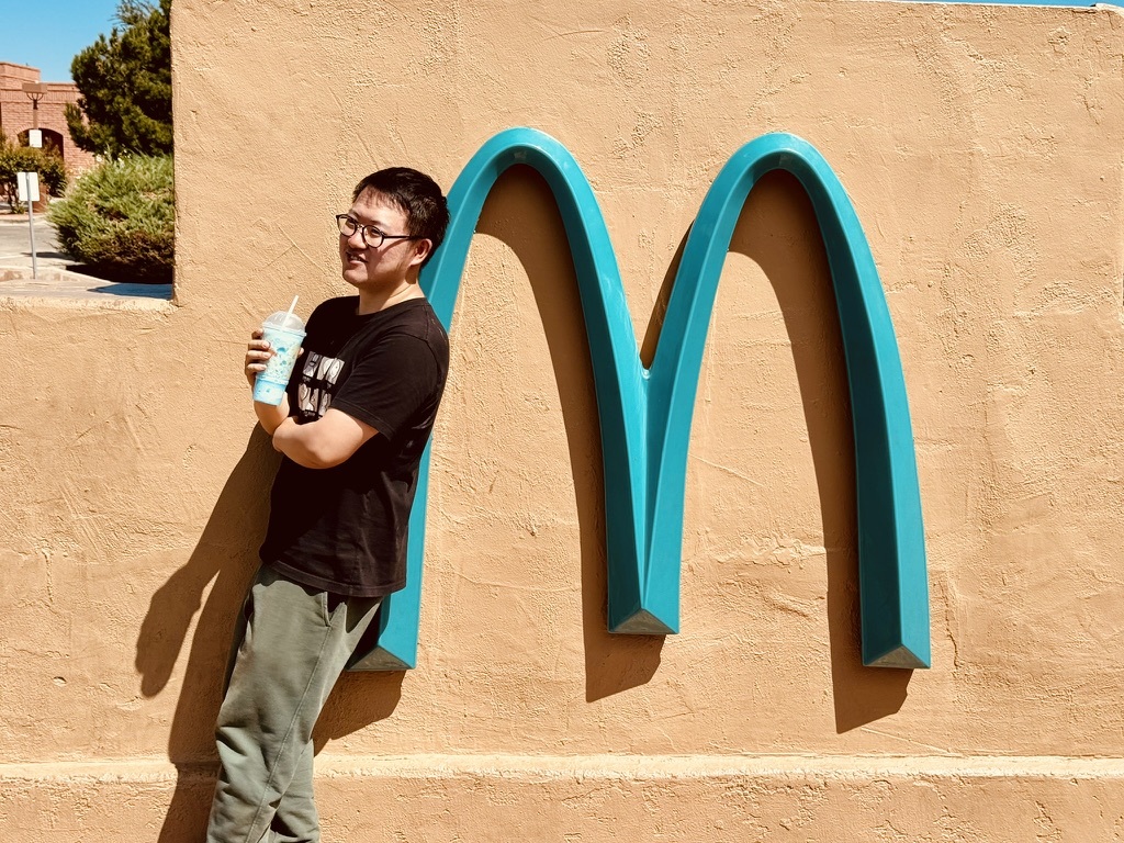 Wenbo Xie outdoors beside a turquoise architectural sculpture.